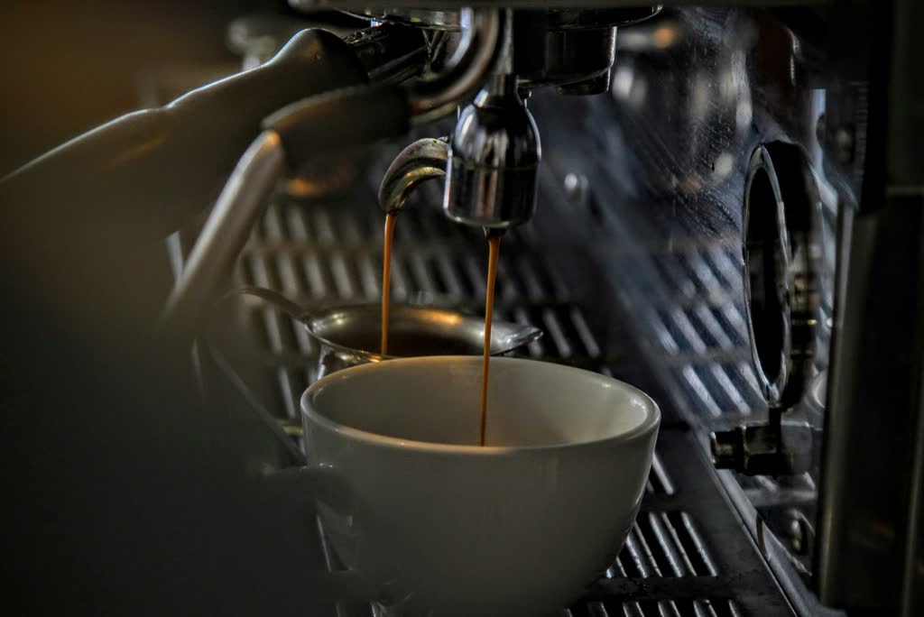 Espresso pouring into a porcelain cup at the bar